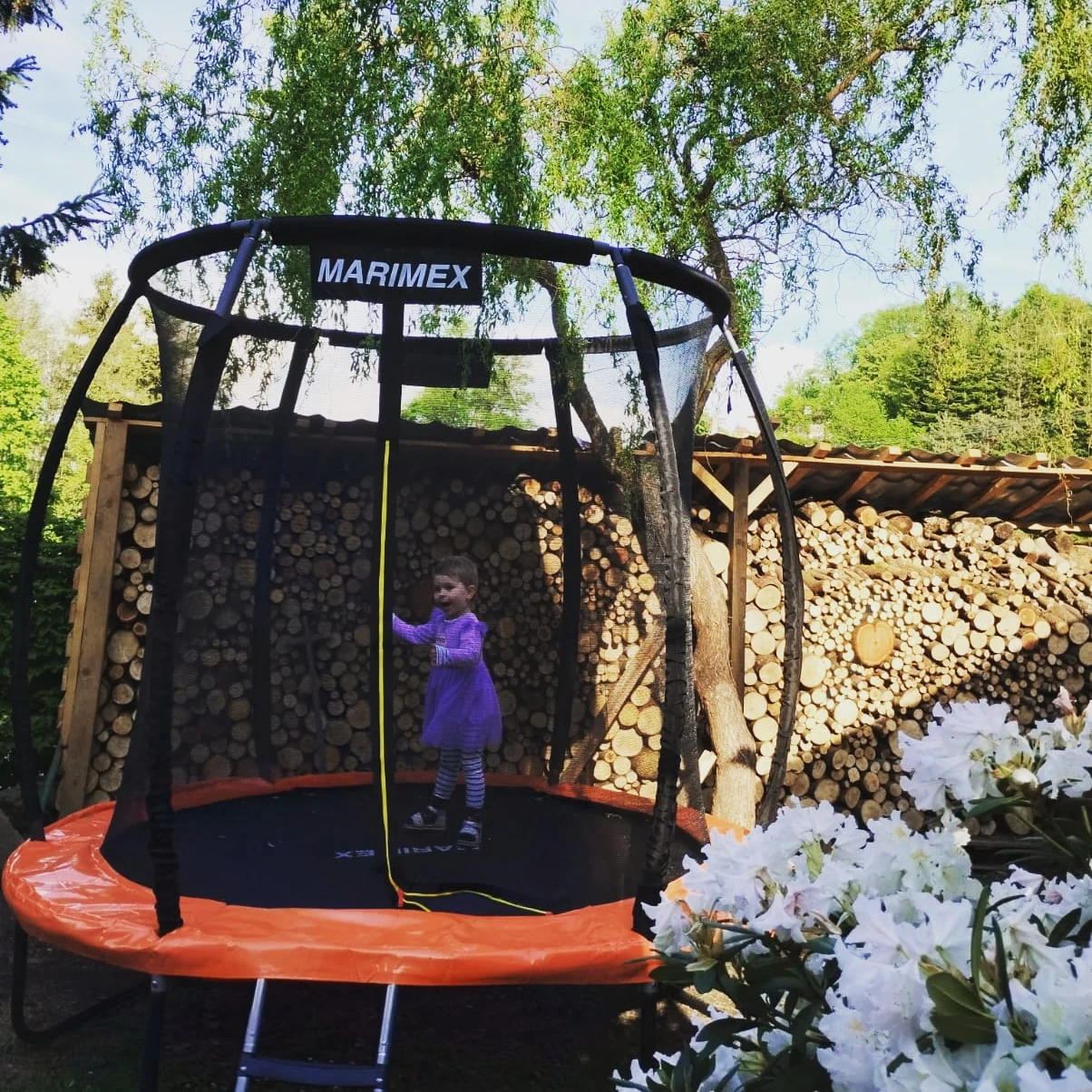 Dítě na trampolíně s ochrannou sítí na zahradě chalupy